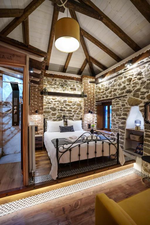 a bedroom with a bed and a stone wall at Archontiko Theofanous 1915 in Tríkala