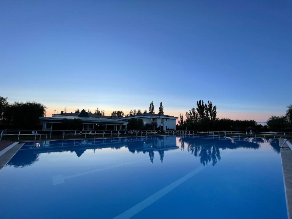 a large pool of blue water with a house in the background at Hotel Valjunco in Valencia de Don Juan