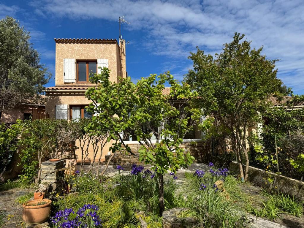 un jardin avec des arbres et des fleurs devant une maison dans l'établissement Maison Zen & Plage, à La Londe-les-Maures