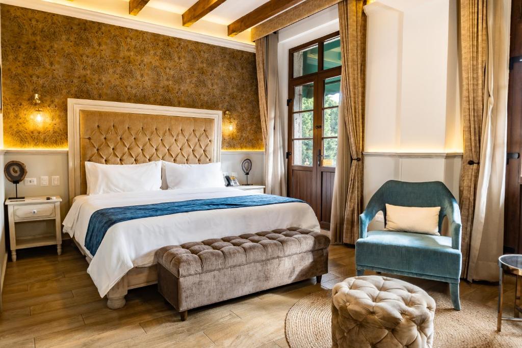 a bedroom with a large bed and a blue chair at voco Royalty Puebla Downtown by IHG in Puebla