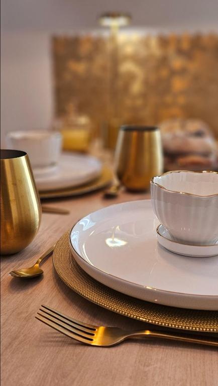une table avec des assiettes, un bol et une fourchette dans l'établissement LoveRoom by LimousineLyonnaise, à Rive-de-Gier