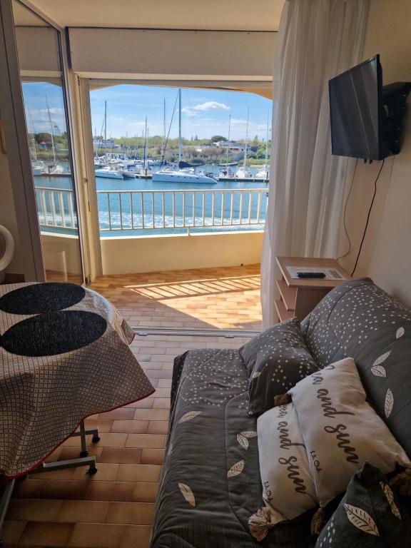 a living room with a couch and a view of a boat at Studio les pieds dans l'eau in Cap d'Agde