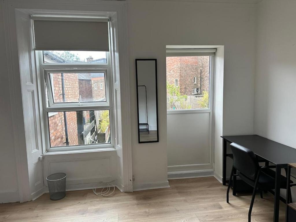 a room with a mirror and a table and two windows at Spacious 3-Bed Flat in Jesmond in Jesmond