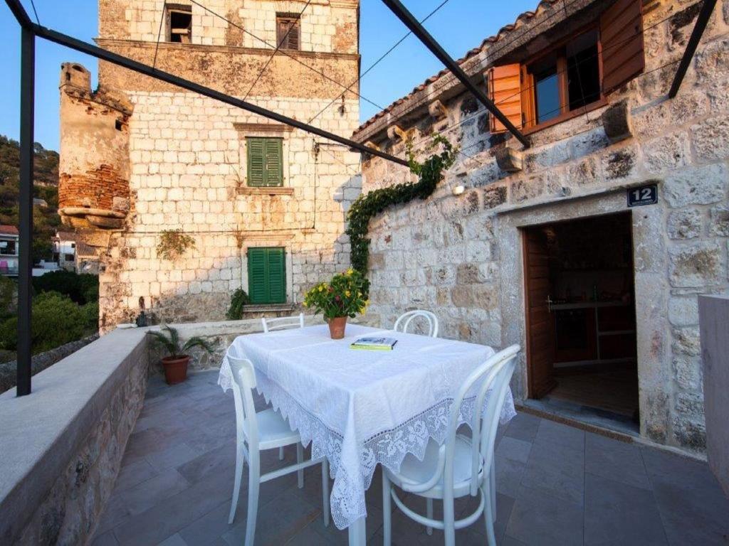 a white table and chairs in front of a building at Authentic Stone House Kut in Vis