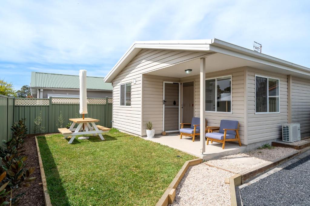a small house with a table and chairs in a yard at Cute Coastal 2-Bedroom Getaway in Ettalong Beach