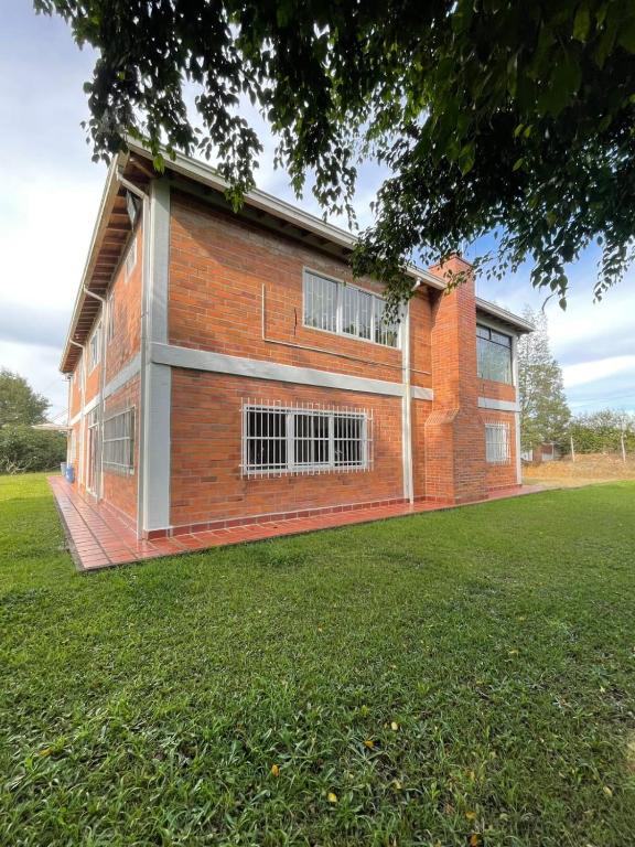 a red brick building with a grassy field in front of it at Finca campestre de 2 pisos en Guarne in Guarne
