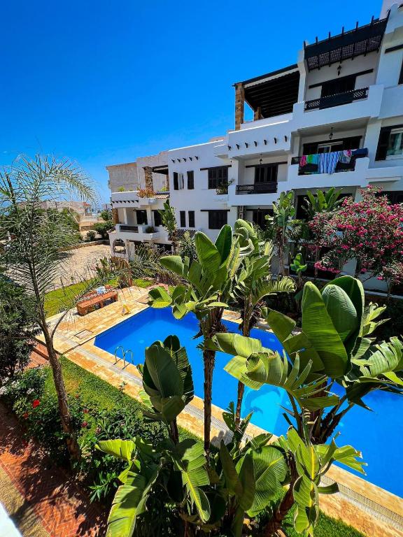 an apartment with a swimming pool in front of a building at Visit Chamal - Oualya in Oued Laou