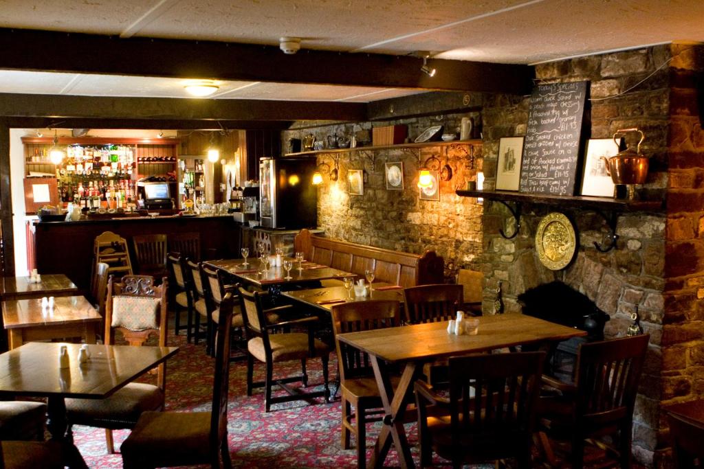 um restaurante com mesas e cadeiras e um bar em Fox and Pheasant Inn em Armathwaite