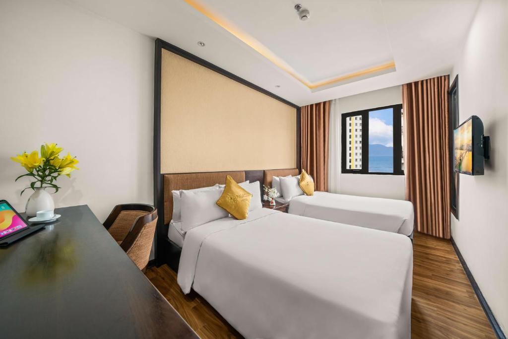 A twin room with two beds, a work desk and a window overlooking buildings and mountains.