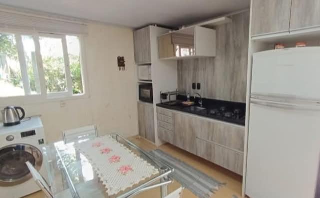 eine Küche mit Glastisch und Kühlschrank in der Unterkunft House Tais in Gramado