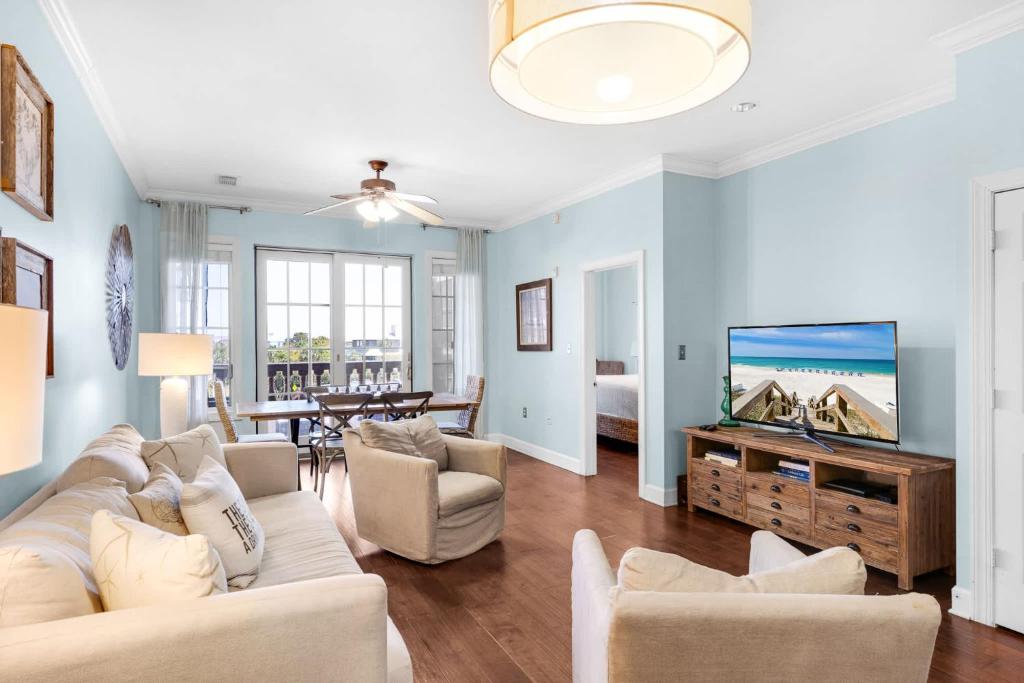 a living room with a couch and a flat screen tv at The Village Blue Haven Condo - Private Beach Access Pool & Hot Tub in Rosemary Beach