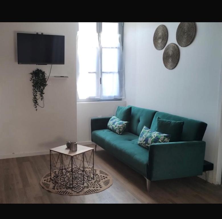 un salon avec un canapé vert et une table dans l'établissement L' Urbain- Centre ville - Climatisé, à Montluçon
