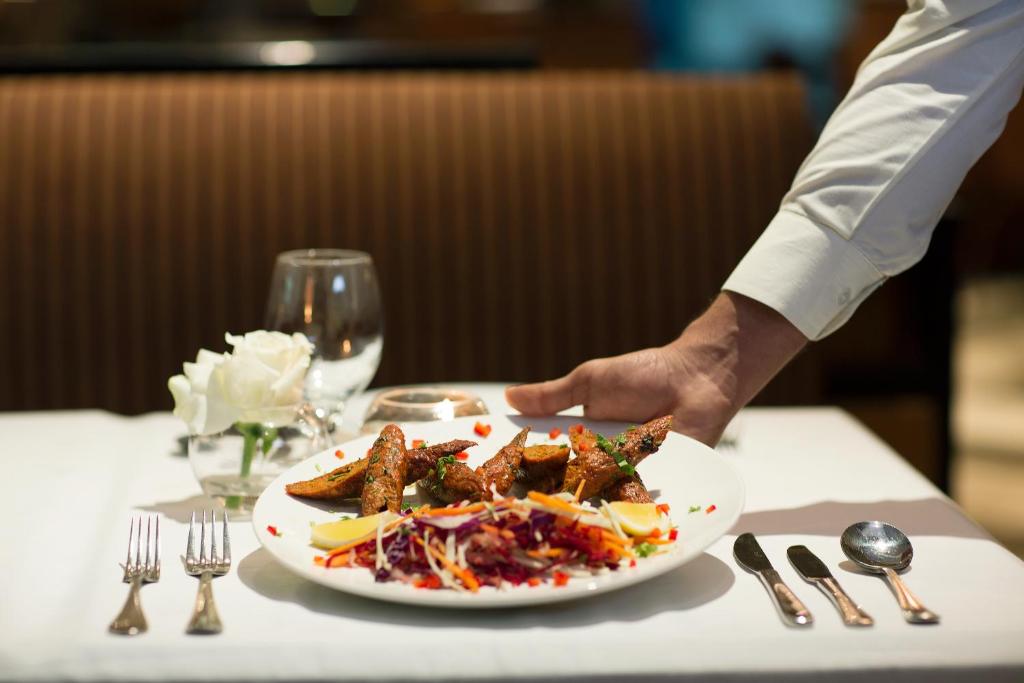 a chef holding a plate of food on a table at Gateway Hotel in Dubai