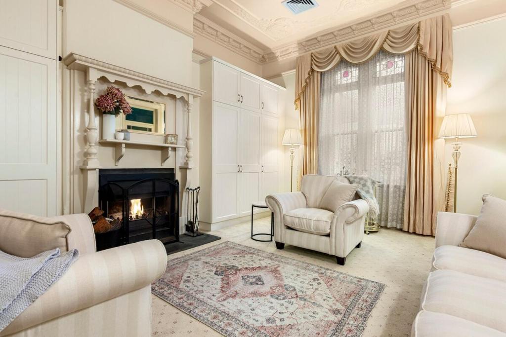 Washington Cottage في Angaston: غرفة معيشة مع كرسيين ومدفأة