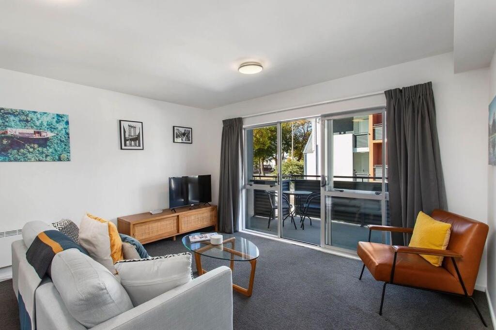 a living room with a couch and a tv at Handy CBD Covered Free Parking Gym 2 Bdrm in Christchurch