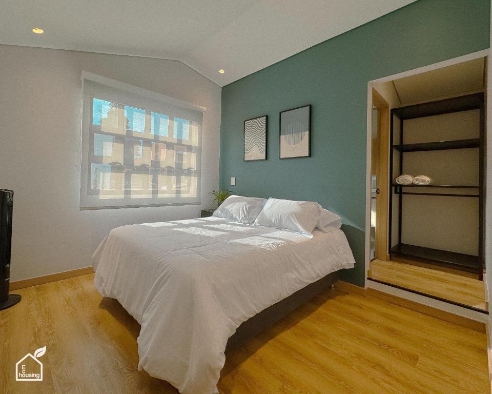 une chambre avec un grand lit blanc avec une fenêtre dans l'établissement Ecohousing, à Medellín