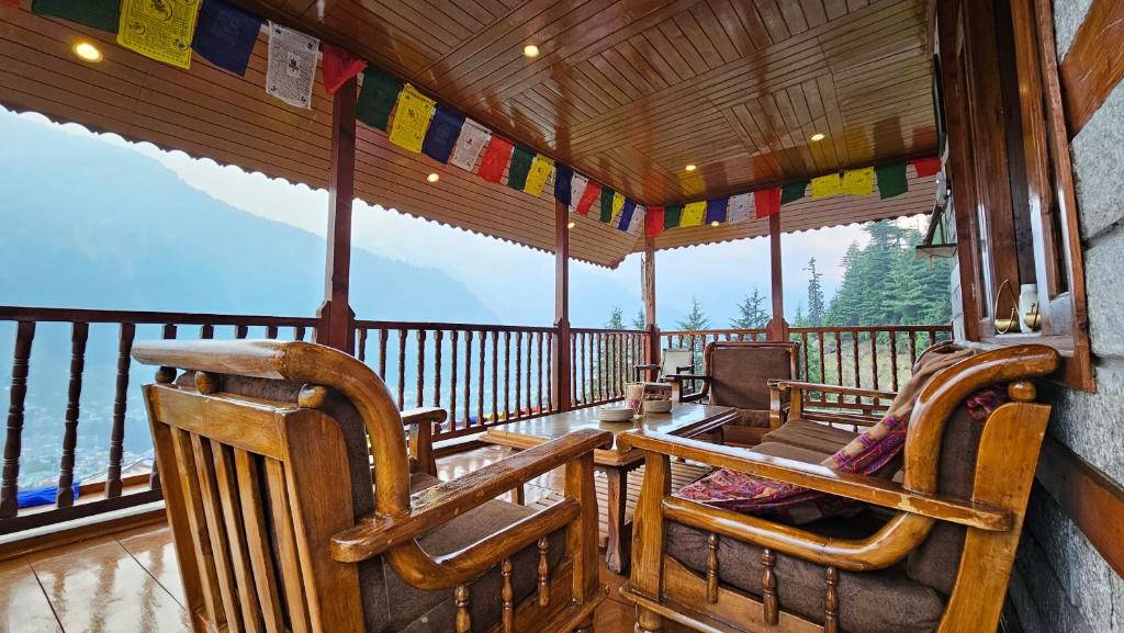 a screened in porch with a table and chairs at Khwabgaah Manali in Manāli