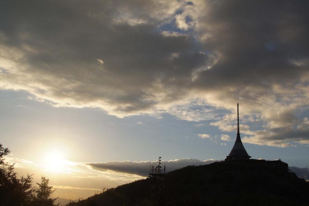 a building on a hill under a cloudy sky at Hotel Ještěd in Liberec