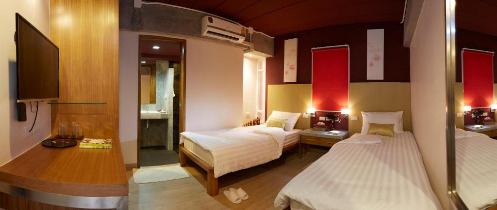 a hotel room with two beds and a bathroom at Uncle Loy's Boutique House in Bangkok