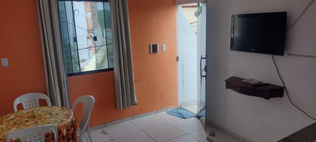 a dining room with a table and a television on a wall at Cantinho Feliz in Arraial do Cabo