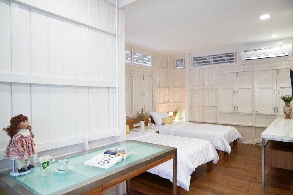a room with two beds and a glass table at Uncle Loy's Boutique House in Bangkok