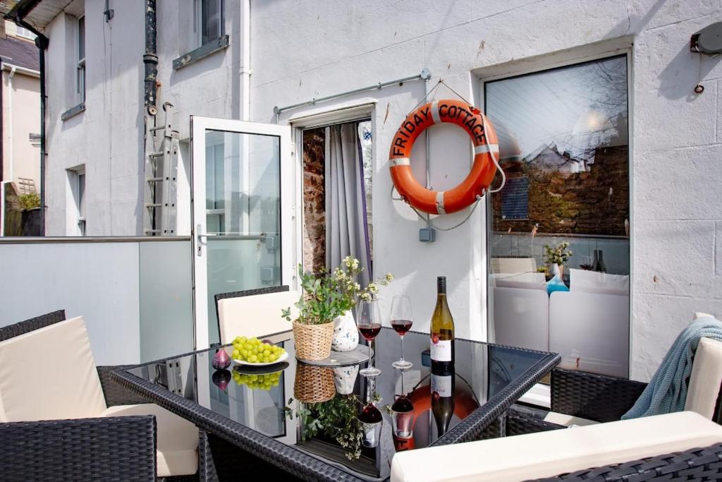 a balcony with a glass table with wine bottles at Friday Cottage - Brixham in Brixham