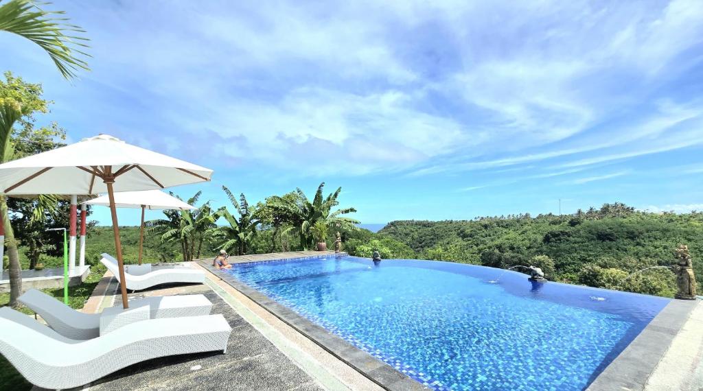 ein Swimmingpool mit zwei Stühlen und einem Sonnenschirm in der Unterkunft Kelingking BMS Penida Hills Villa in Nusa Penida