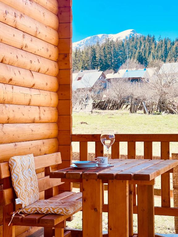 a wooden table with a glass of wine on a deck at Alfa Omega Žabljak in Žabljak