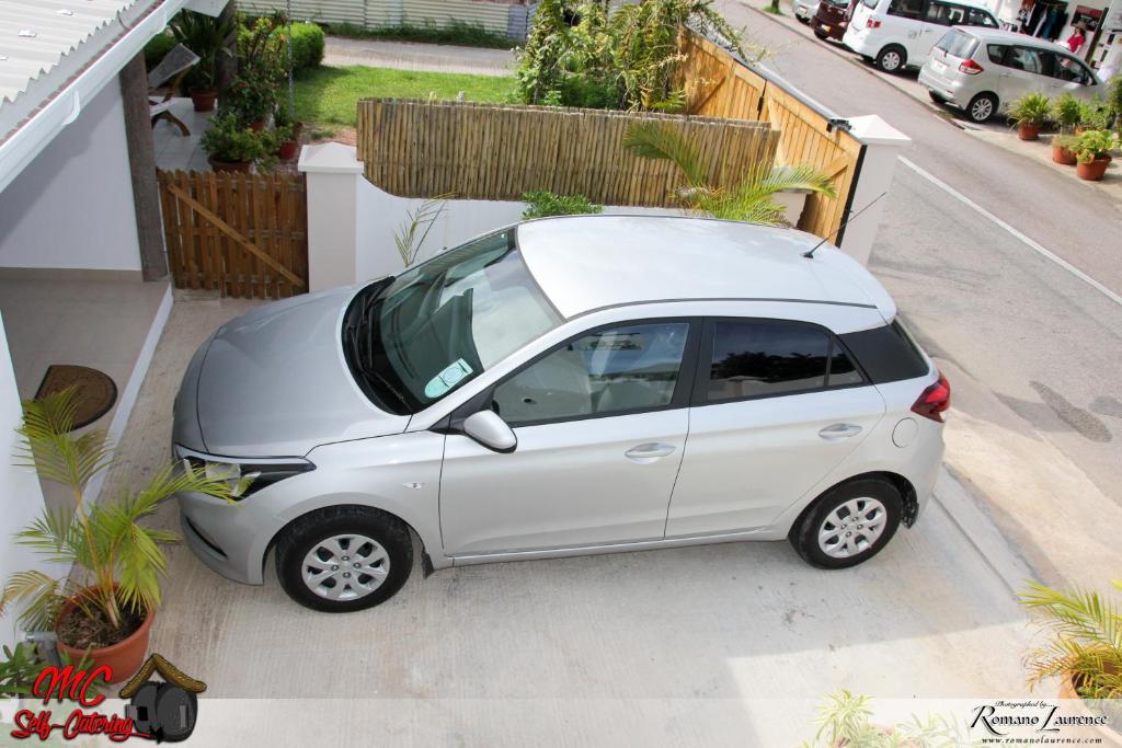 a small white car parked on the side of a street at MC Self Catering in Baie Sainte Anne