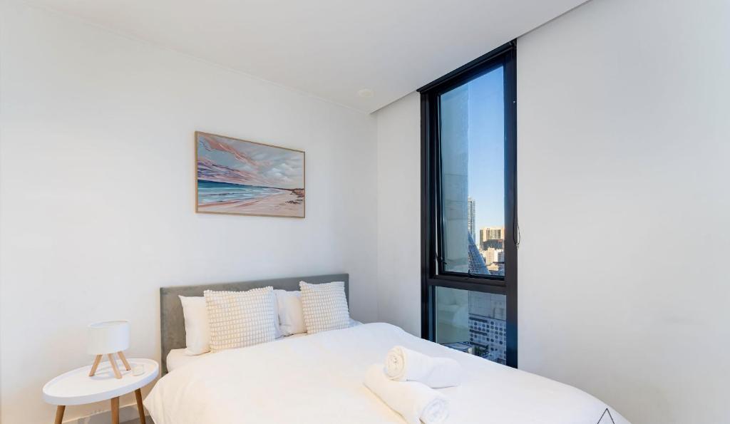 Un dormitorio con una cama blanca y una ventana. en CityNest Melbourne, en Melbourne