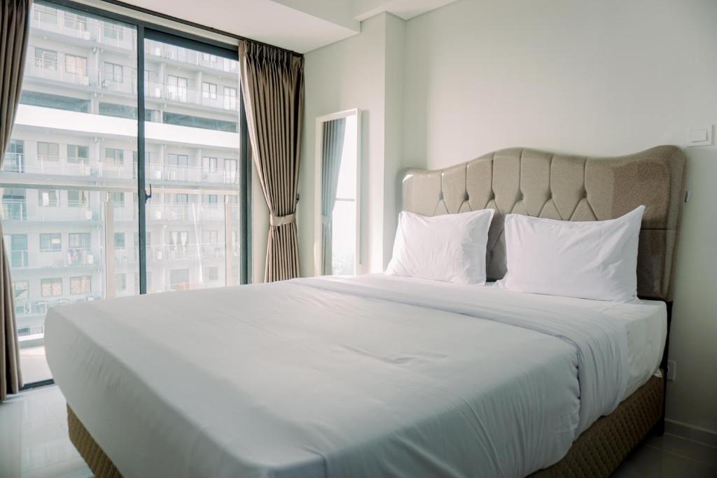 a bedroom with a large bed with a large window at Pleasurable and Tidy Studio Daan Mogot City Apartment By Travelio in Jakarta
