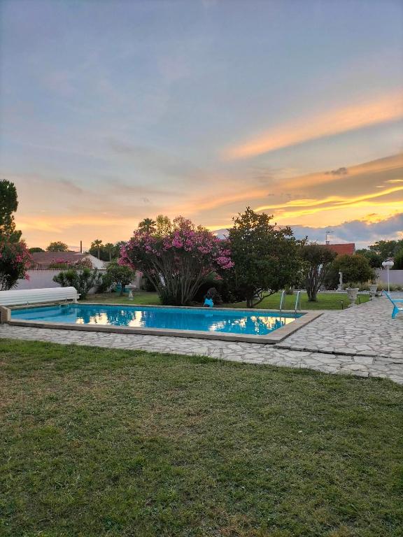 - une piscine dans une cour avec un coucher de soleil dans l'établissement La paillote des Ninous, à Bassan