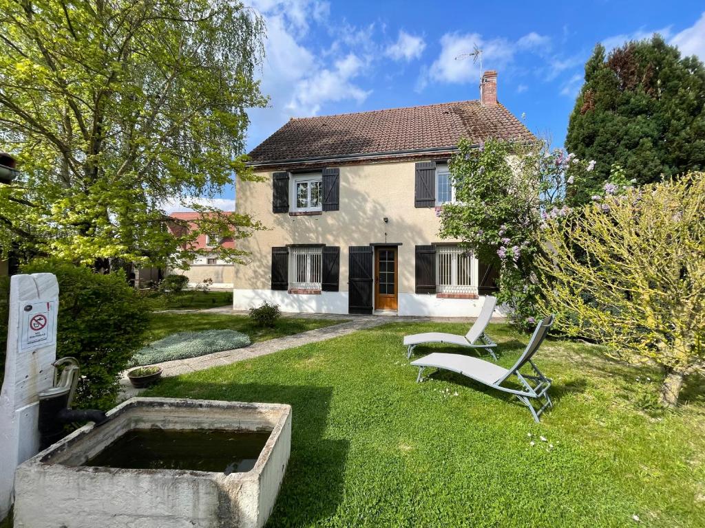 a house with a garden with two chairs in the yard at Gîte Le Calyaden in Athis