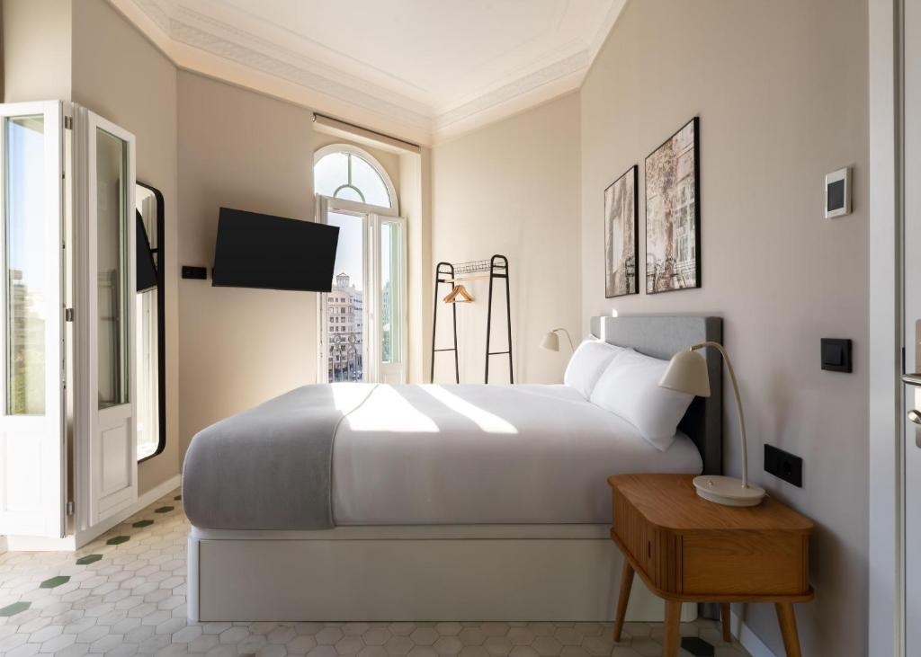 a white bedroom with a large bed and a window at Limehome Valencia de Xativa in Valencia