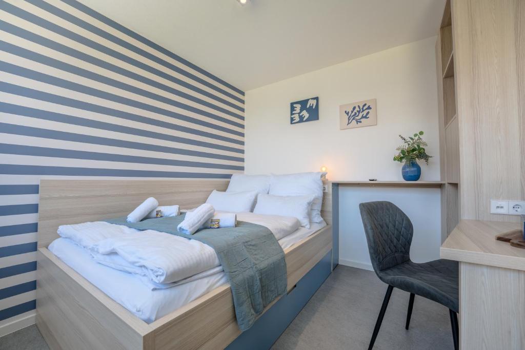a bedroom with a bed with a blue and white striped wall at SCHLOSSBERG RESIDENCES - Bodensee Studio-Apartments Friedrichshafen & Ravensburger Spieleland in Meckenbeuren