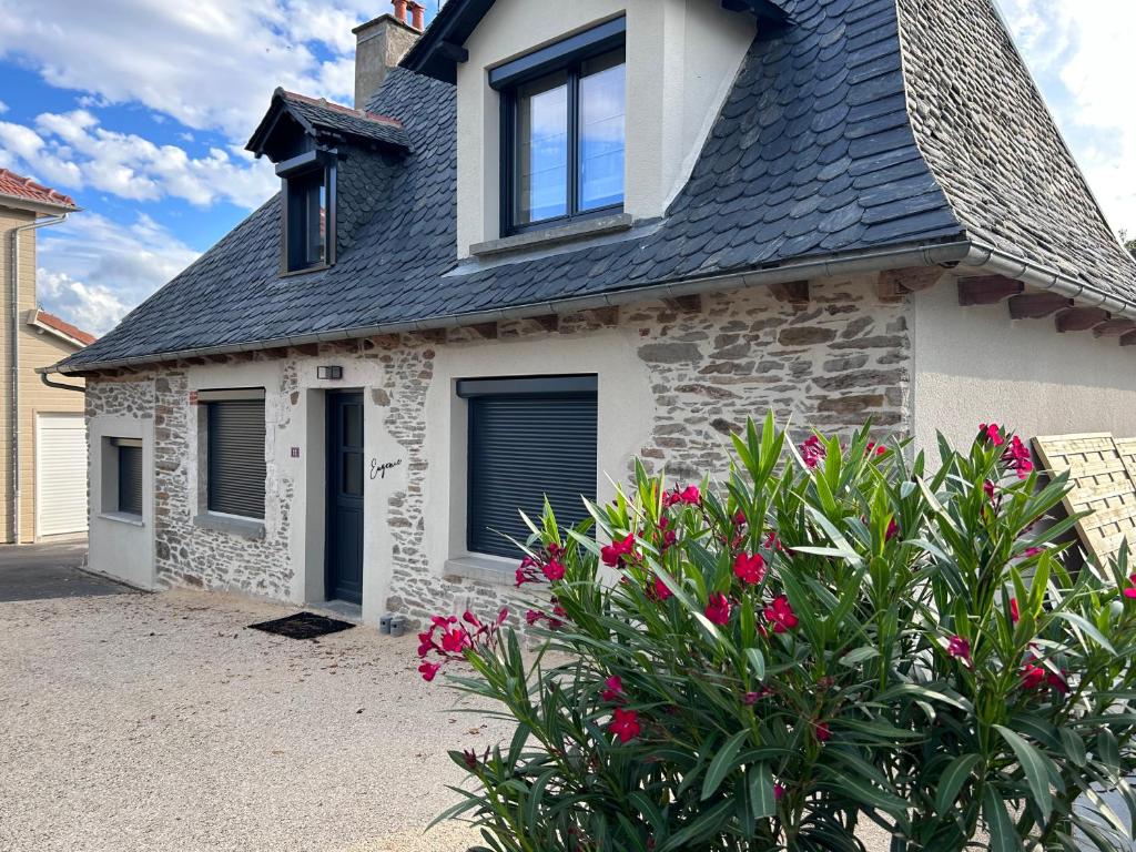 Una casa de piedra con techo negro y algunas flores. en Eugenie, en Labrousse