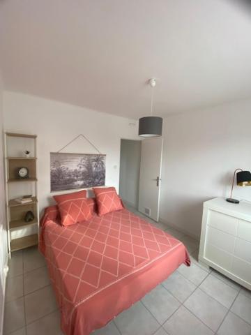 une chambre avec un lit avec une couette rouge dans l'établissement Le Myosotis Route des plages, à Narbonne