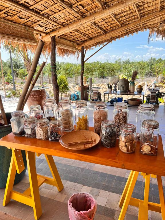 une table en bois avec des bocaux de nourriture dans l'établissement Bently farm retreat Mũi Né- Deluxe Bungalow-01, à Ấp Phú Hiệp