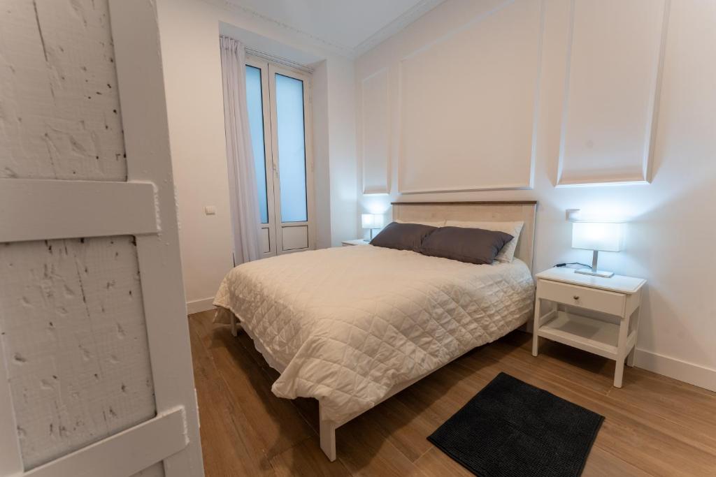 a white bedroom with a bed and a window at La bahia rooms in Santander
