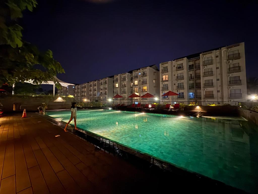 a person standing next to a swimming pool at night at Elixia 3C'S by Planet Path in Sri Jayewardenepura Kotte