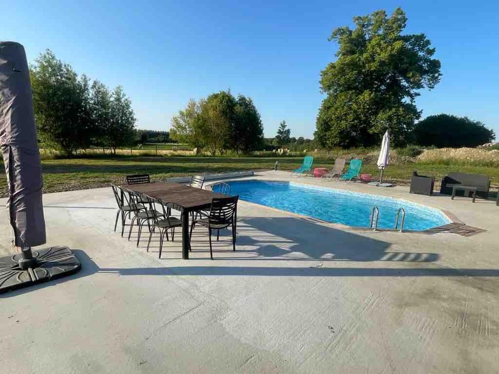- une table et des chaises à côté de la piscine dans l'établissement Grande maison de campagne, à Mézières-sur-Ponthouin