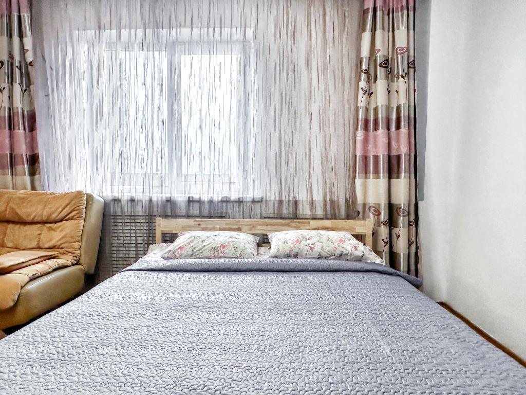 a bedroom with a bed and a window and a couch at 05 Апартаменты в центре города - выбор для туриста и деловых поездок in Almaty