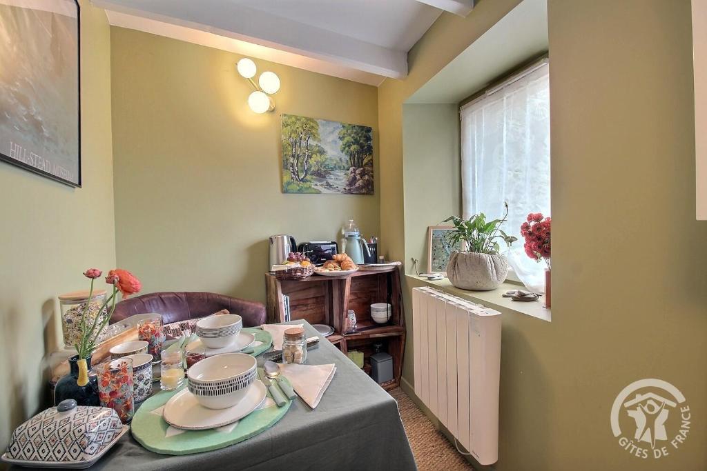 a dining room with a table with dishes on it at La petite maison de dom in Pleslin-Trigavou