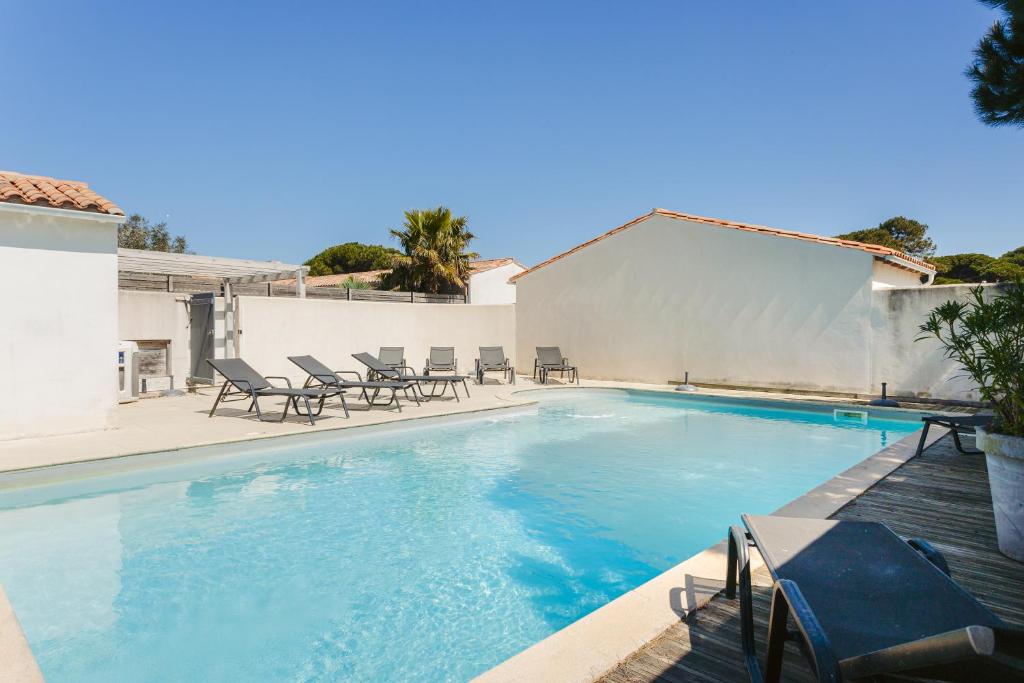 een zwembad met stoelen en een tafel en een gebouw bij Maison N°3 - Résidence Pingettes in Le Bois-Plage-en-Ré