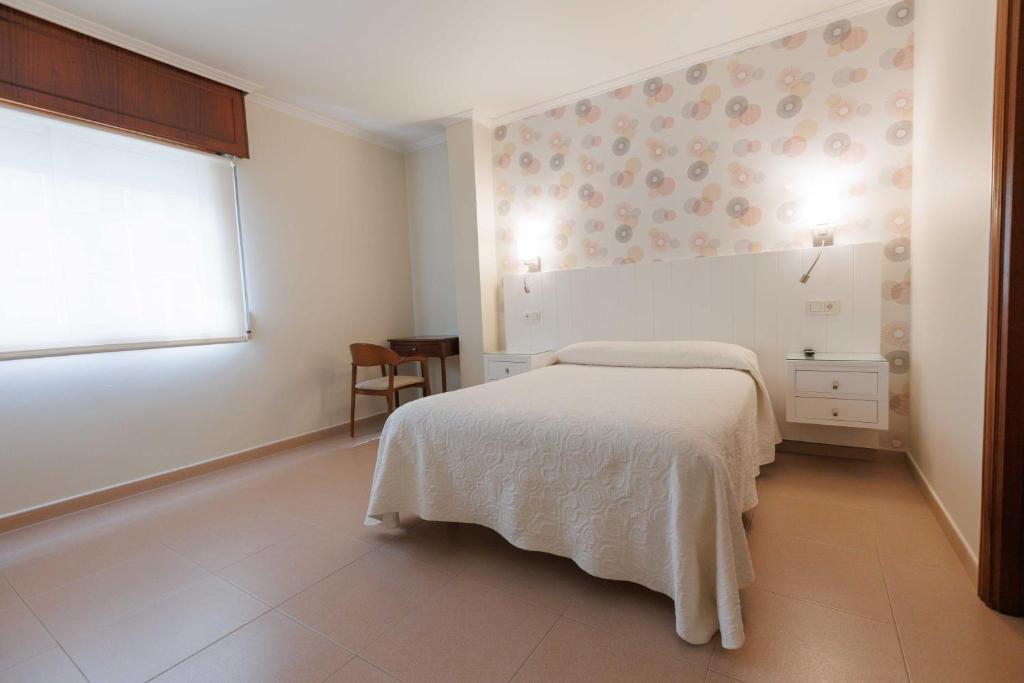 a white bedroom with a bed and a window at Hotel O Cruceiro in Caldas de Reis