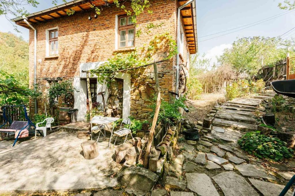 Una casa de ladrillo con un camino de piedra al lado de un edificio. en Къща за Гости Марго, en Kosti