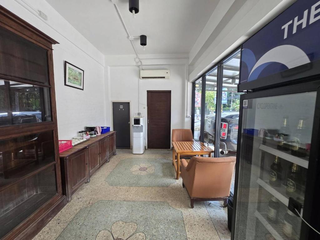 A compact hotel lobby with a coffee counter, armchairs, a drinks cooler and street-facing glazing.