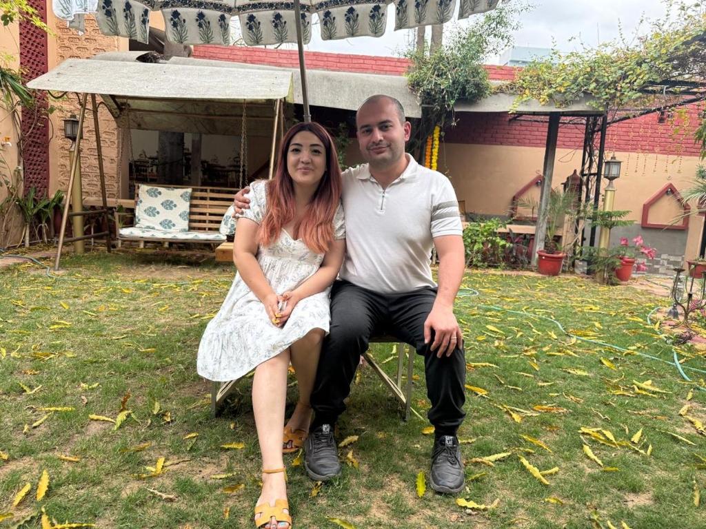a man and a woman sitting on a chair under an umbrella at Travellers Village-City Center Hertige Home in Jaipur