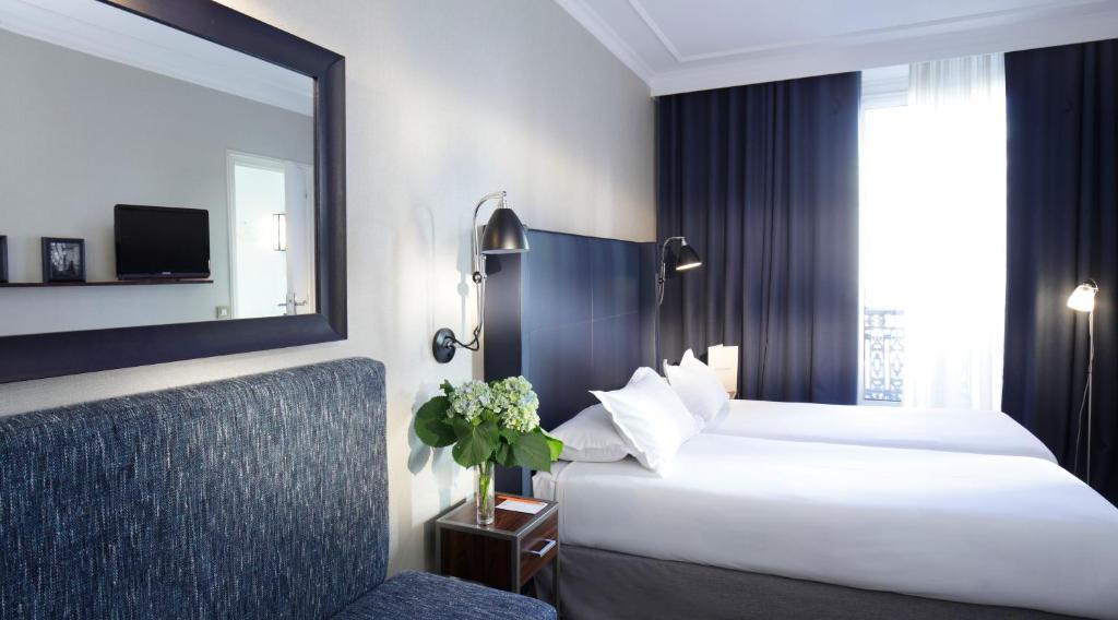 a hotel room with a large bed and a mirror at Hôtel Londres et New York - Teritoria in Paris