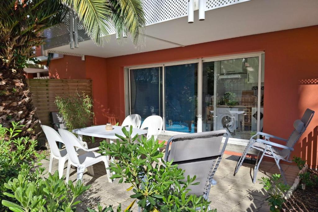 d'une terrasse avec des chaises blanches et une table. dans l'établissement Studio Pinasse - Welkeys, à Arcachon